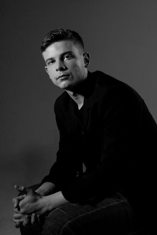 Free Elegant black and white portrait of a young man in a dark suit, conveying seriousness. Stock Photo
