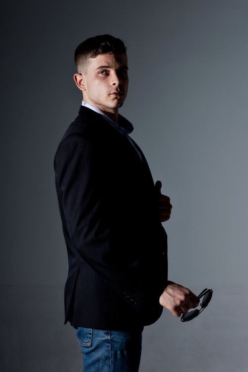 Free Portrait of a stylish man holding sunglasses in a moody studio setting, Belo Horizonte. Stock Photo