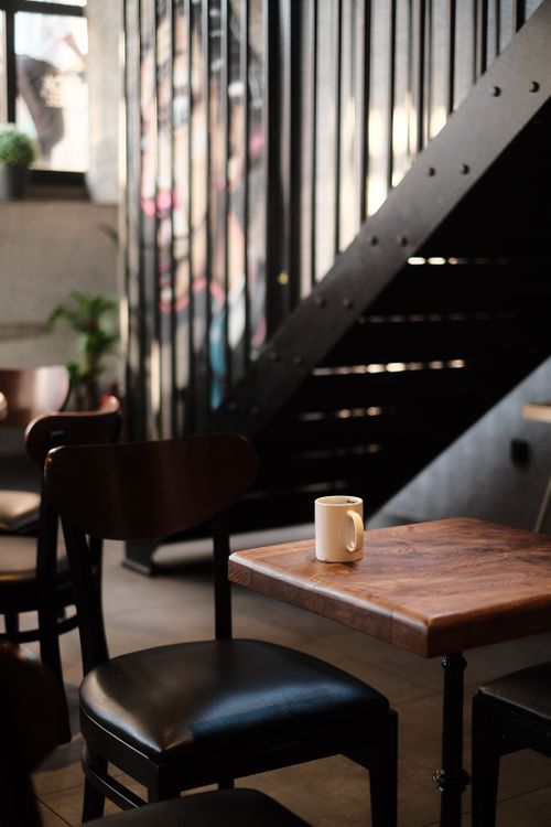 Free Warm and inviting corner of a coffee shop with wooden furniture and ambient lighting. Stock Photo