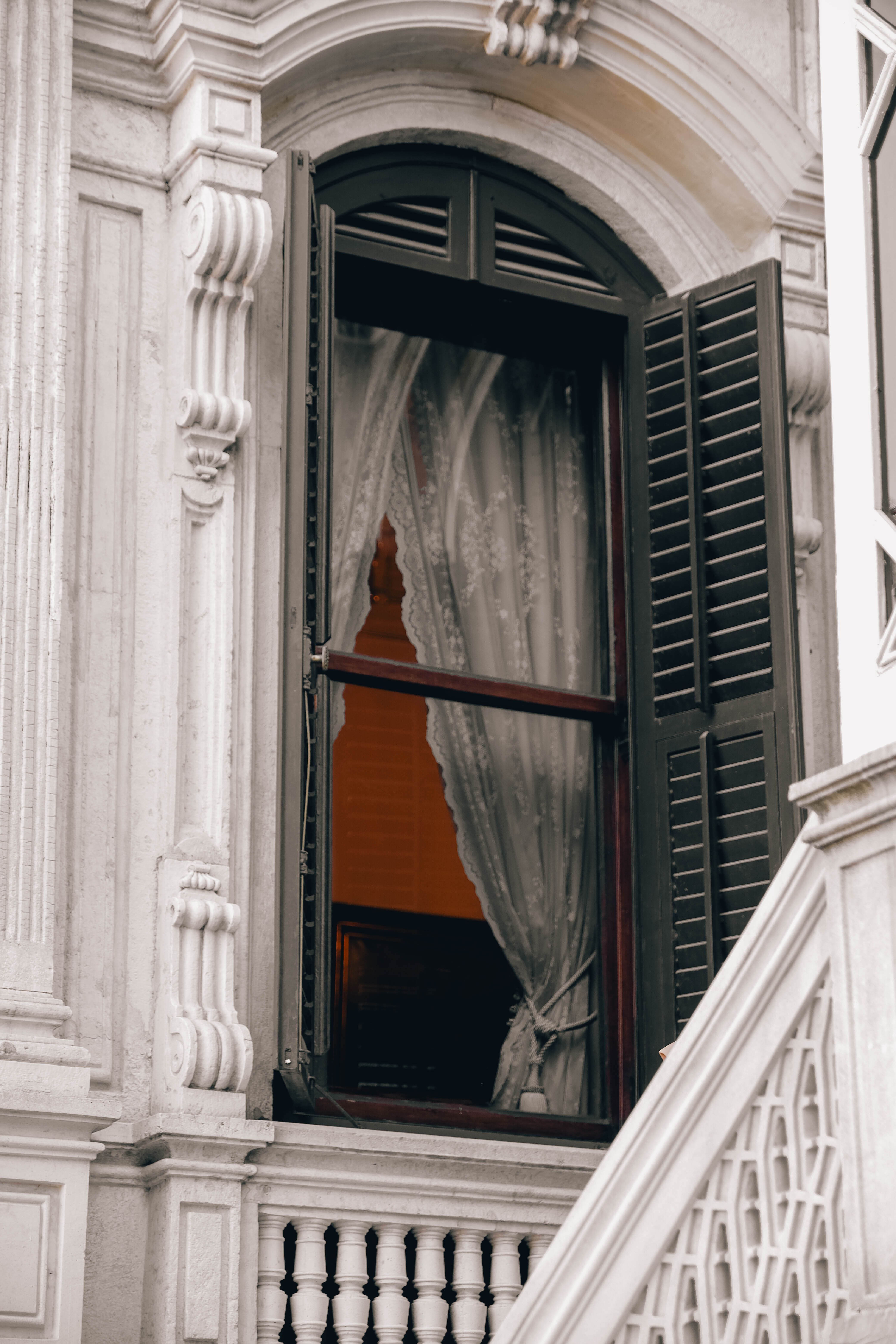 A window with curtains and a white railing · Free Stock Photo
