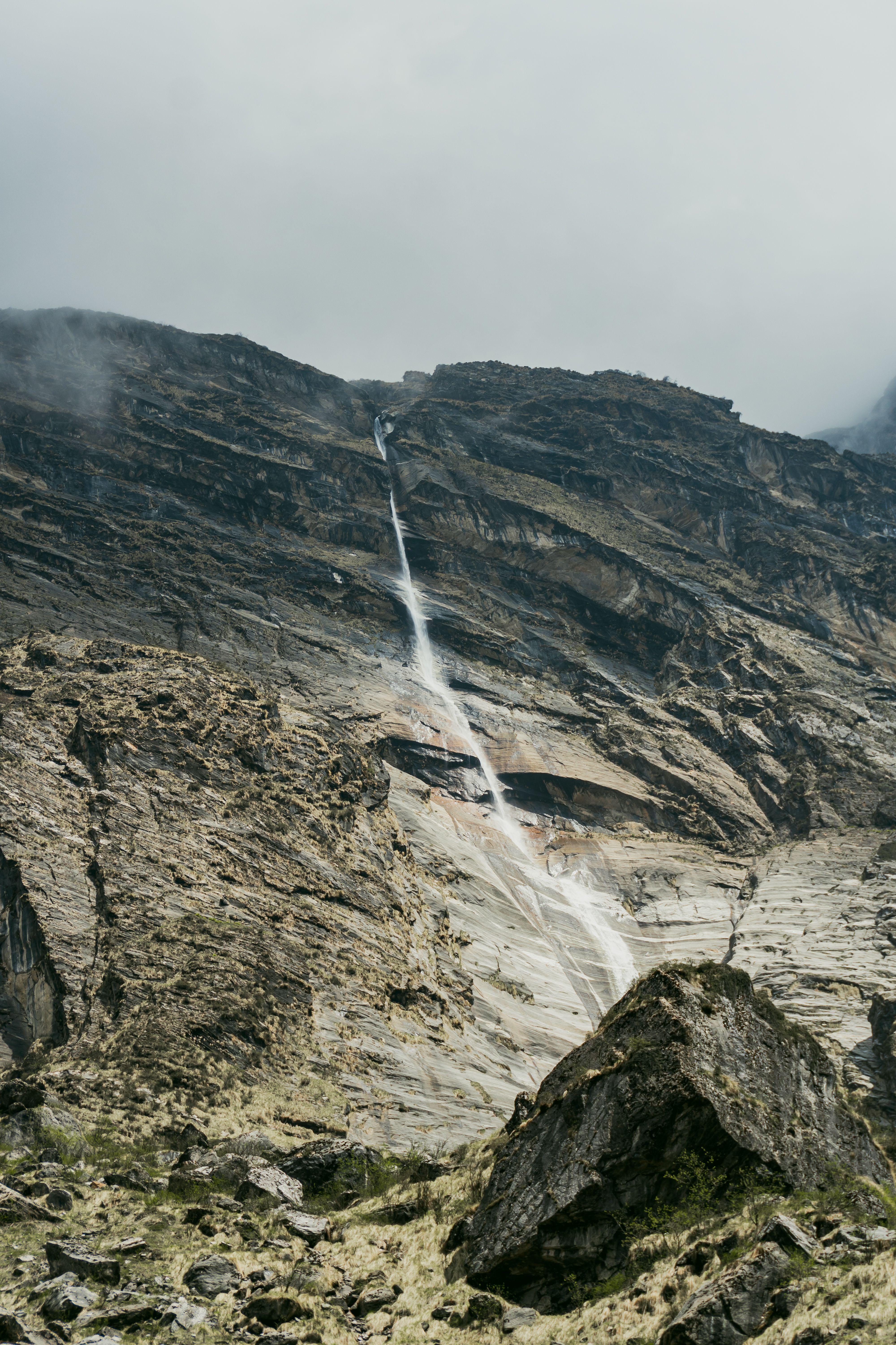 A waterfall is flowing down a mountain · Free Stock Photo