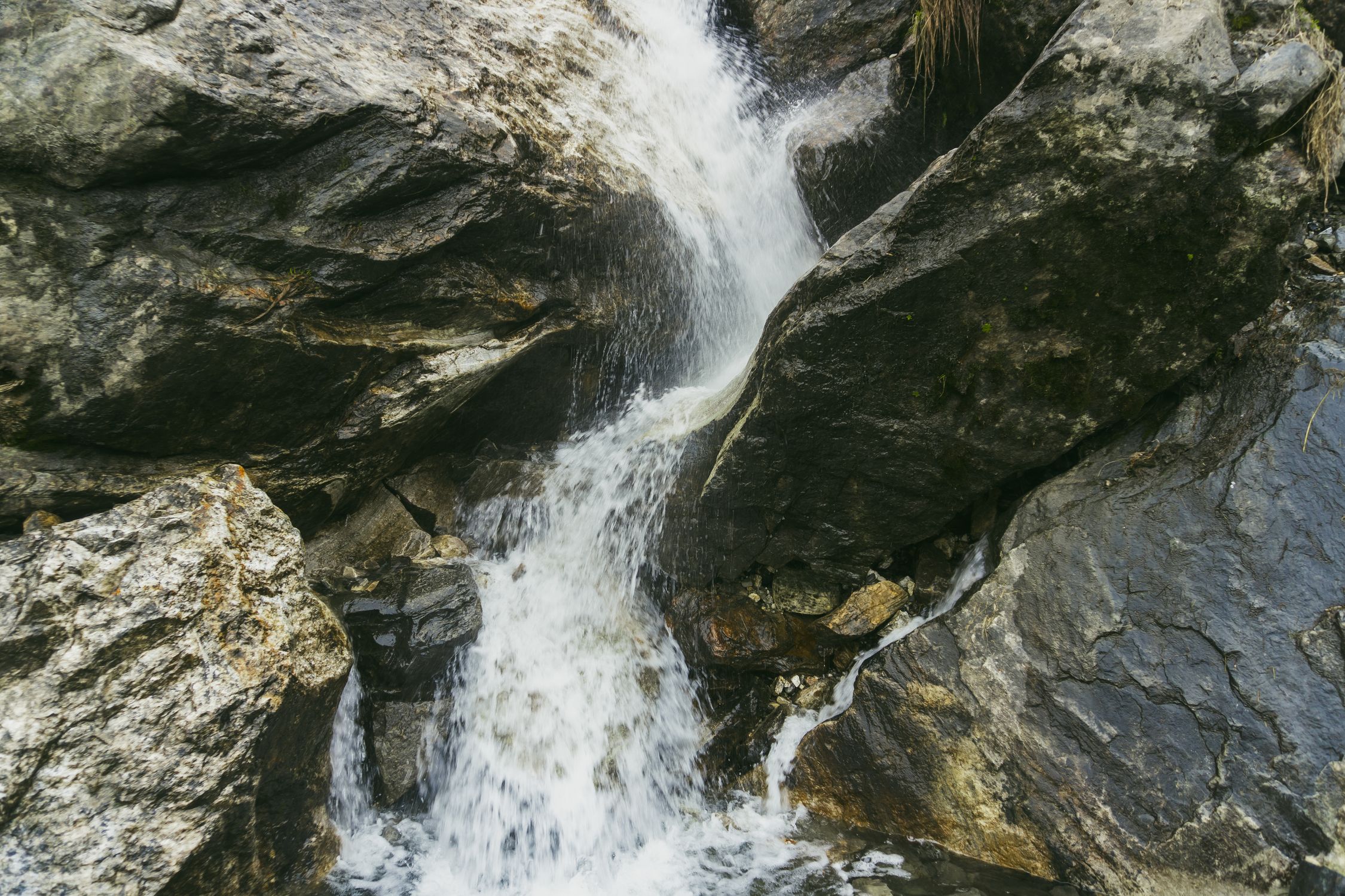 A waterfall flowing over rocks in a forest · Free Stock Photo
