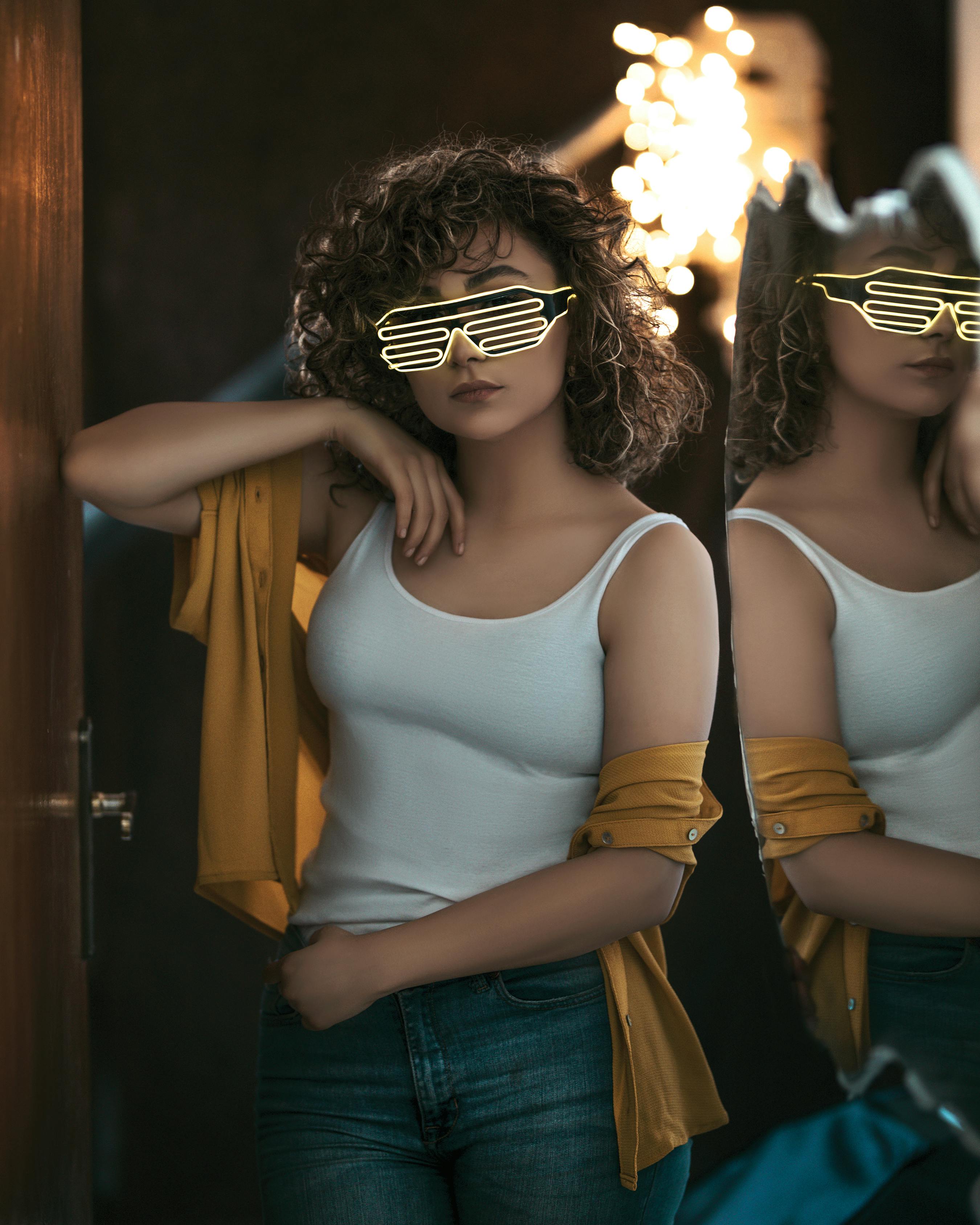 一位时尚的卷发女性自信地戴着霓虹灯太阳镜，身着休闲装