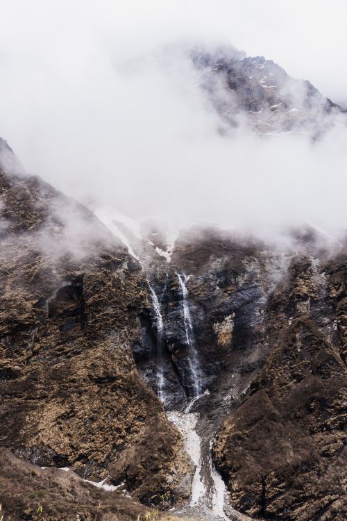 Free Cloud-covered mountain with a waterfall in Ghandruk, Nepal. Stock Photo