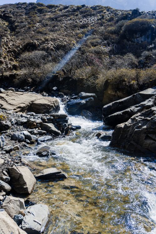 Free A clear mountain stream flowing through rocky terrain in Ghandruk, Nepal, during the day. Stock Photo