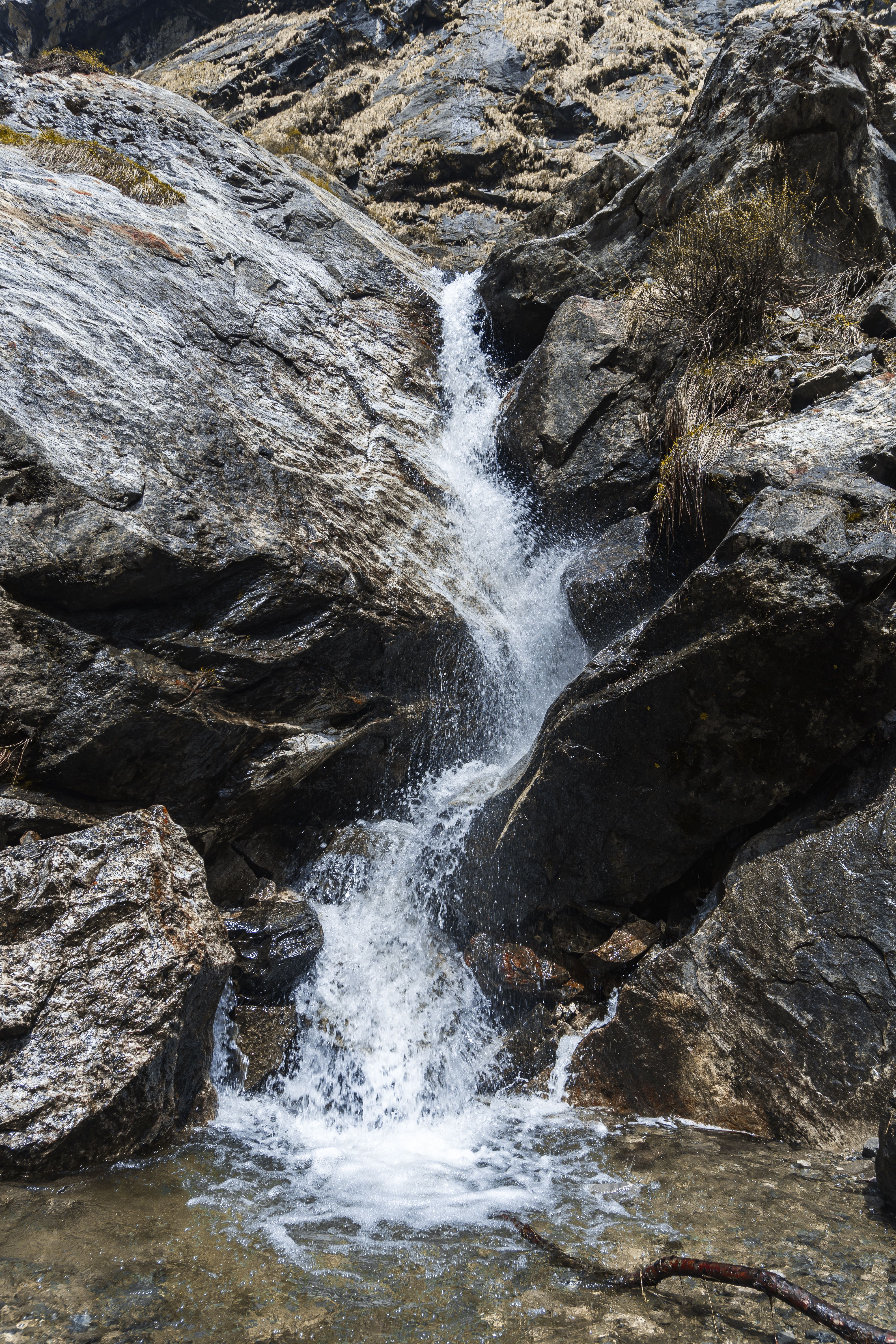 A waterfall is flowing down a rocky mountain · Free Stock Photo
