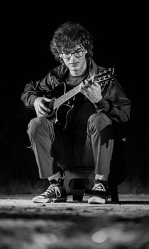 Black and white portrait of a guitarist playing an acoustic guitar during a live performance.