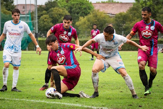 Players engaged in a competitive soccer match on a rainy day, showcasing teamwork and strategy.