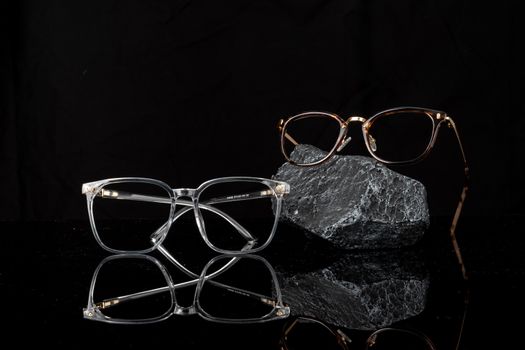 Stylish eyeglasses showcased on a reflective black surface, emphasizing modern fashion and optical design.