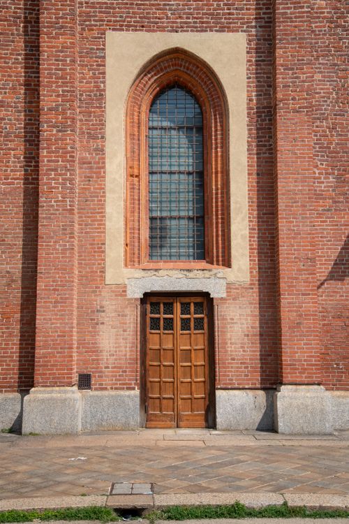 Free Vertical shot of a Gothic church entrance with brick arches in Milan, Italy. Stock Photo