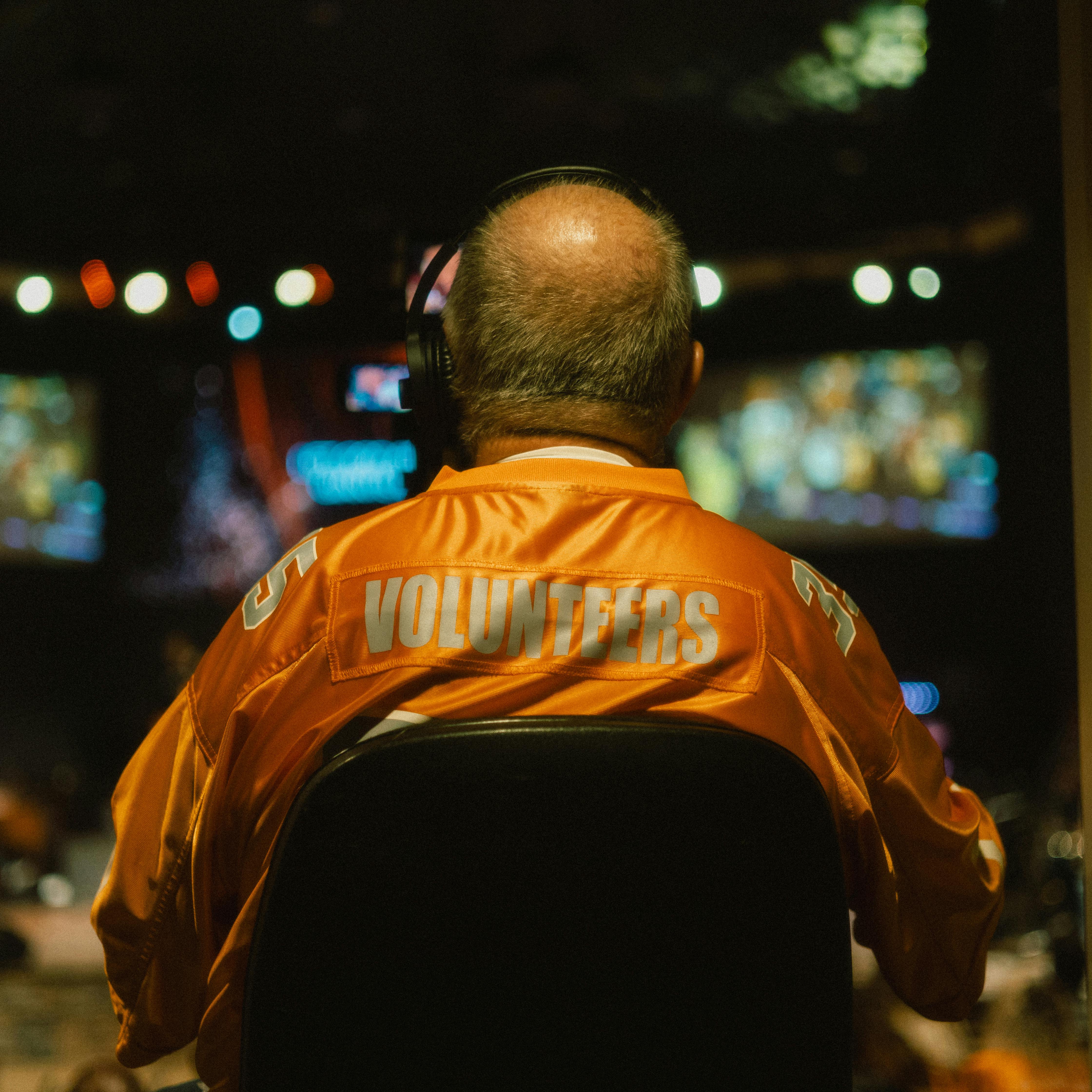 Cameraman wearing an orange Volunteers jersey captures a live event in Cleveland, Tennessee.