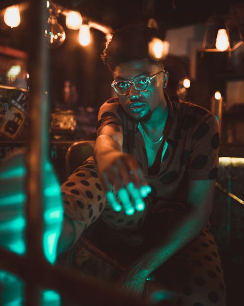 Selective Focus Photography of Sitting Man Under Lamps