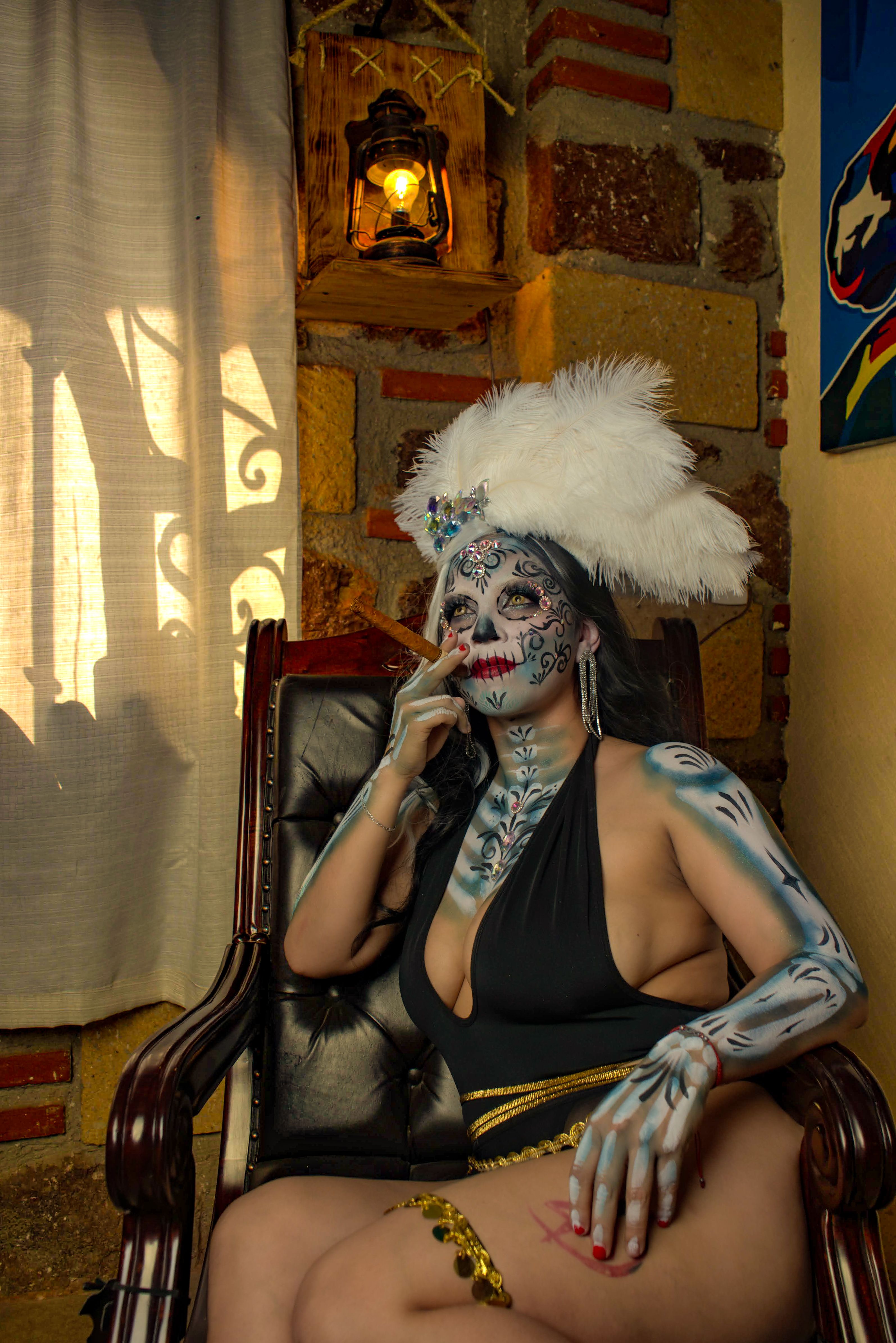 A woman in a La Catrina costume sits elegantly in an indoor setting, embodying the spirit of Mexican tradition.