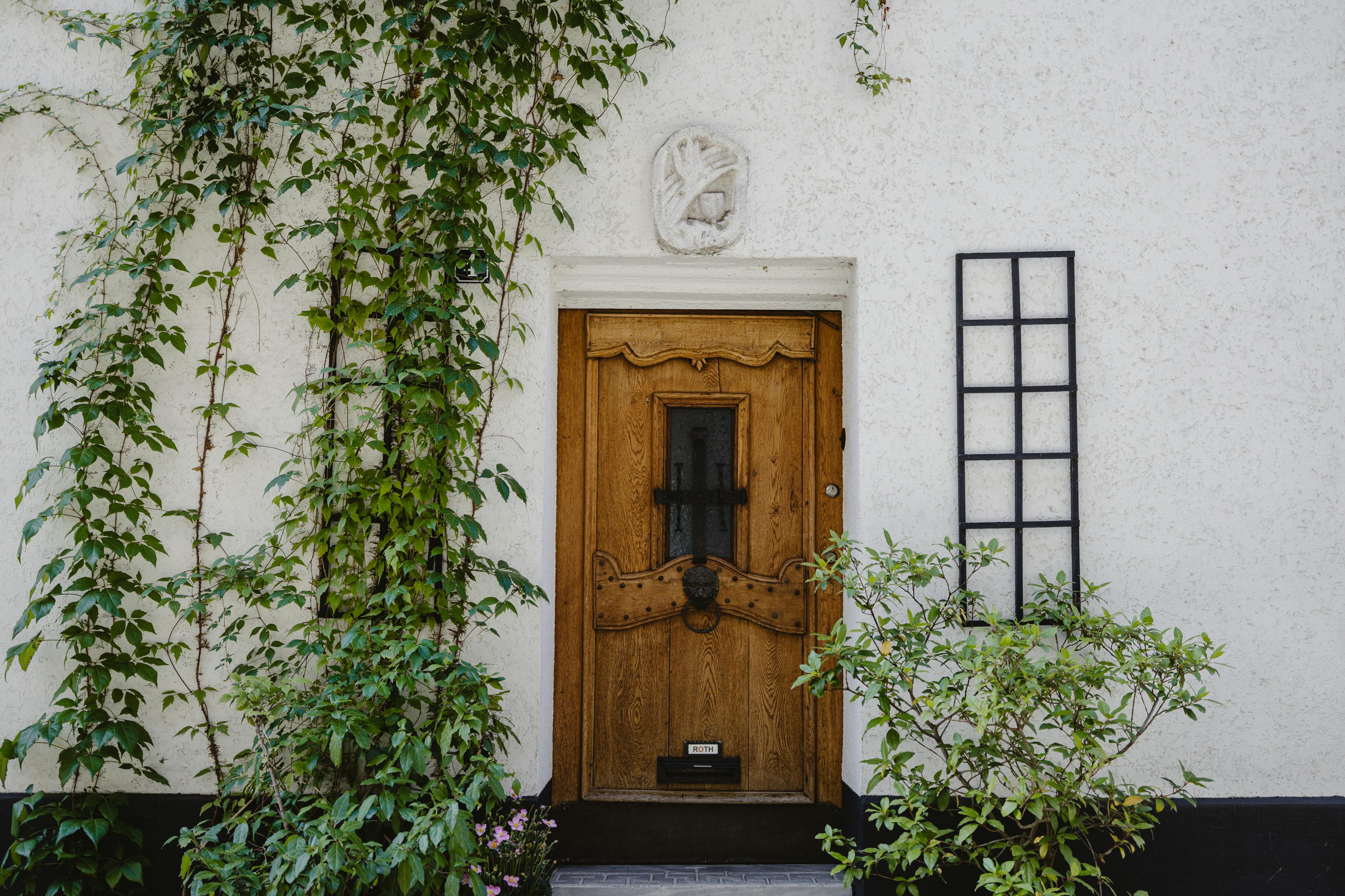 Rustic wooden door with ivy on a traditional Roman building facade.