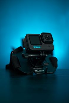 Black action camera mounted on an adjustable head strap with a blue background.