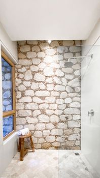 Elegant bathroom with stone wall and glass shower door.