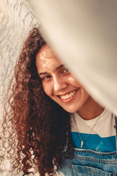 一位卷发的年轻女子在明媚的阳光下灿烂微笑，传递着幸福与温暖