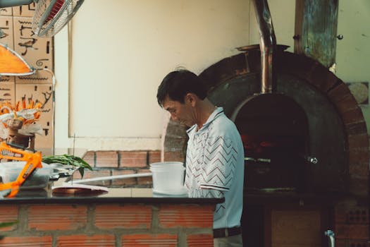 A chef working near a traditional oven in a Vietnamese restaurant kitchen in Dalat.