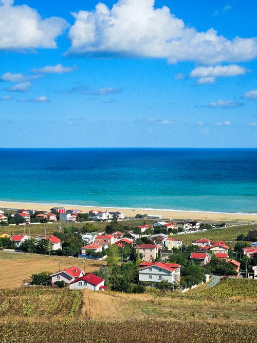Free Aerial view of a charming coastal town overlooking the blue sea and sandy beach under clear skies. Stock Photo