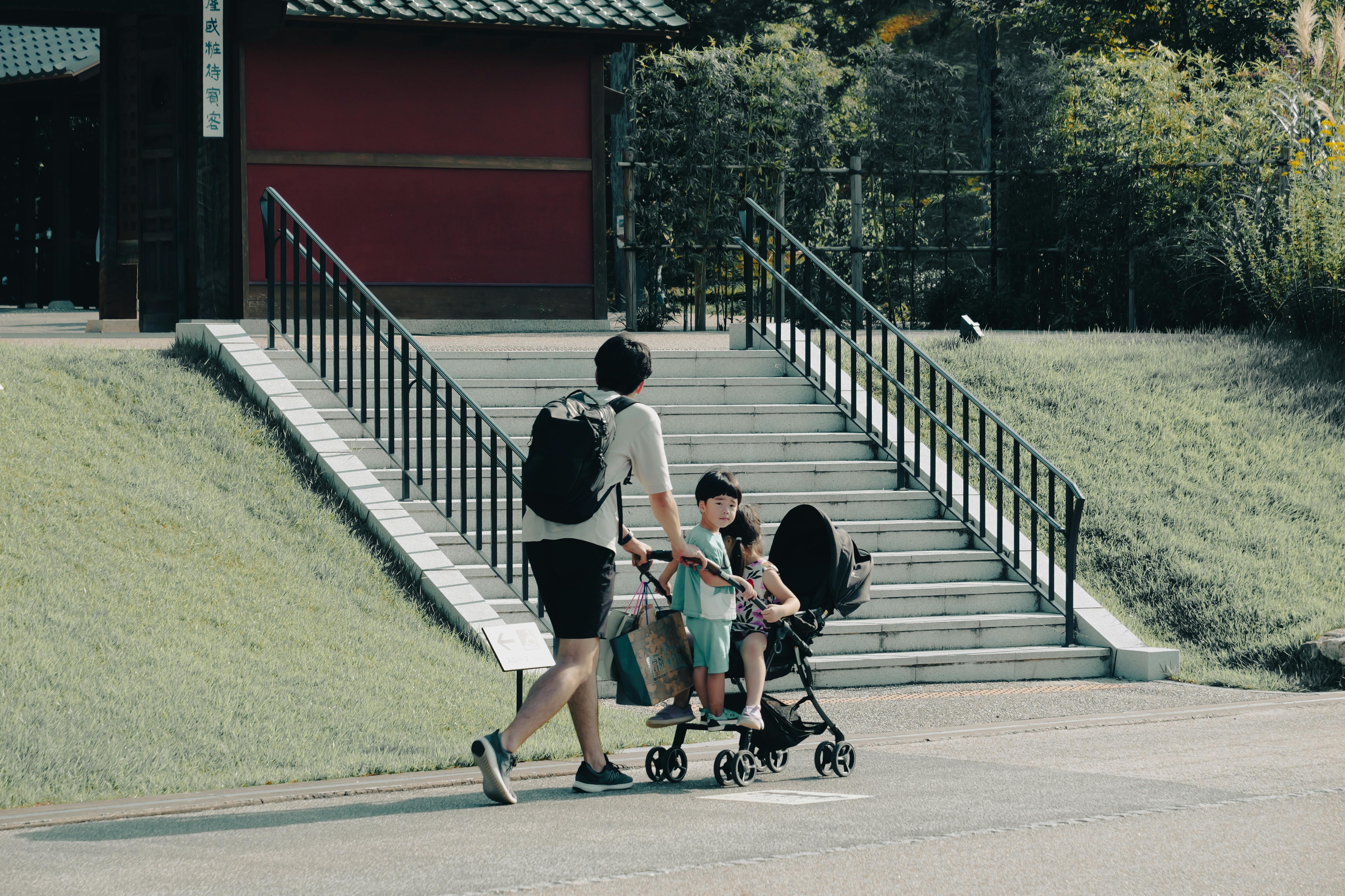 A father pushes a stroller with children on a sunny day in Nagoya, Japan. Outdoor fun and leisure activities.