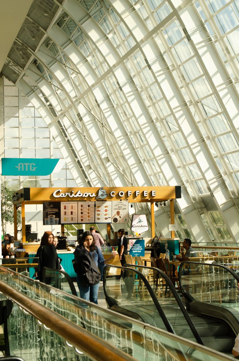 Busy indoor food court with international kitchens under a glass roof