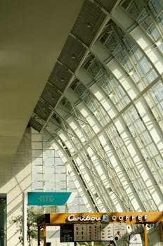 Futuristic airport interior featuring steel and glass design with a Caribou Coffee stand.