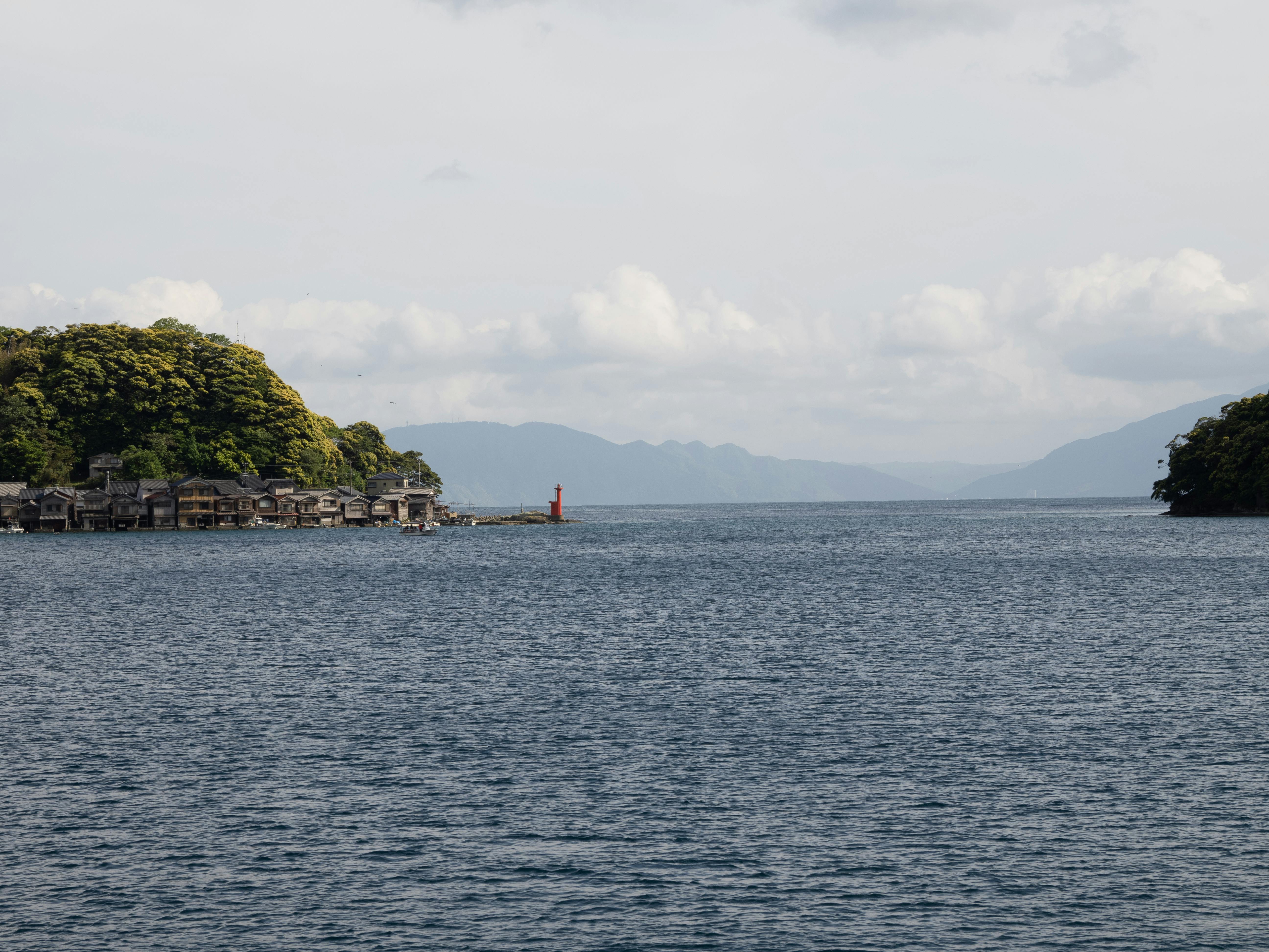 Charming view of Ine Bay with traditional wooden boat houses and a lighthouse in Kyoto, Japan.