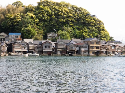 Free Idyllic scene of traditional wooden boathouses in Ine, Kyoto with lush hillside backdrop. Stock Photo