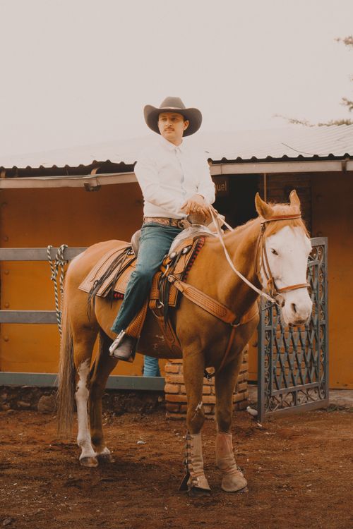 Free A cowboy in a white hat rides a horse outdoors in Mexico City. Stock Photo