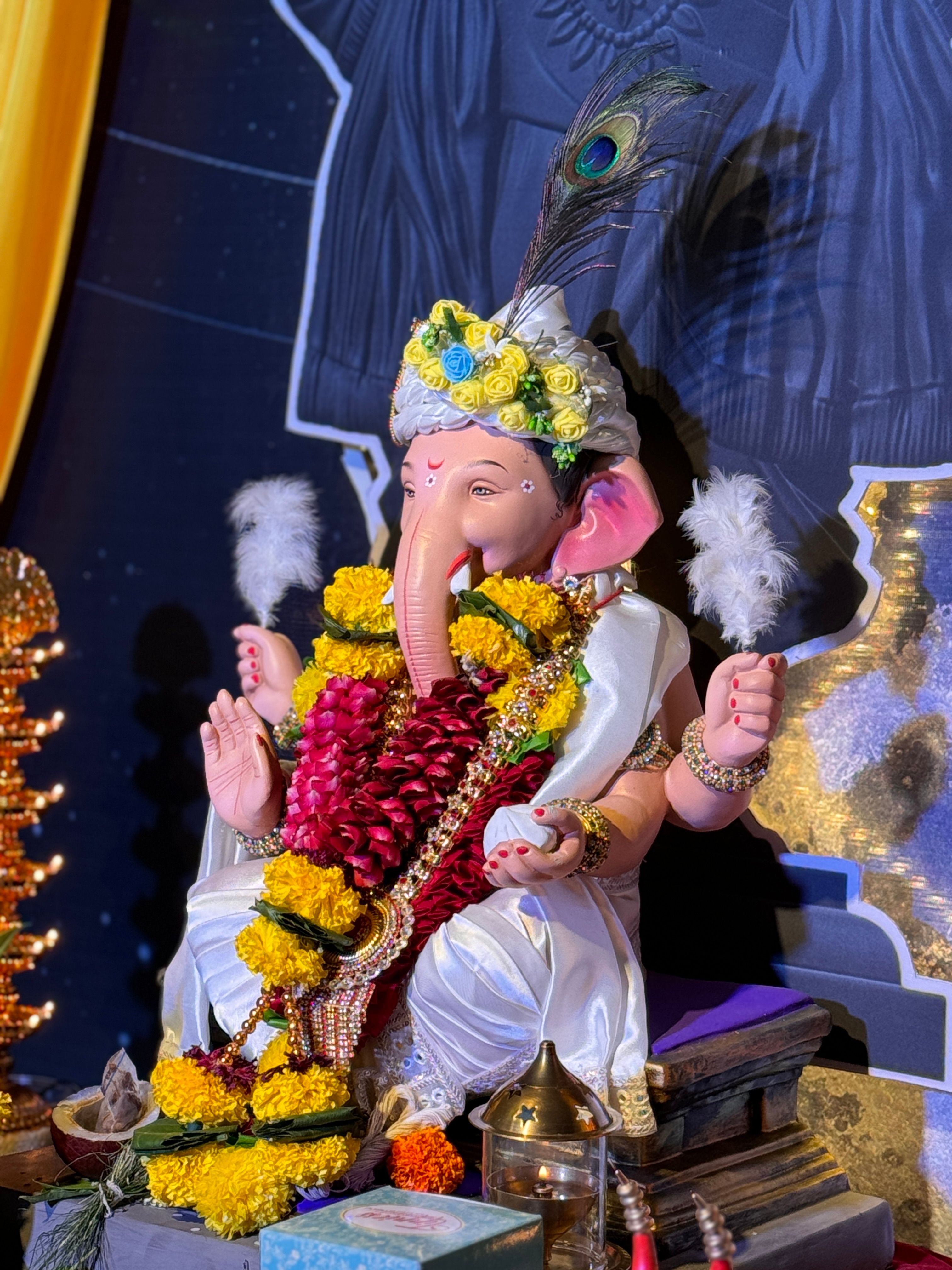 A beautifully decorated Ganesh idol with flowers and peacock feathers, celebrating Ganesh Chaturthi in Mumbai, India.