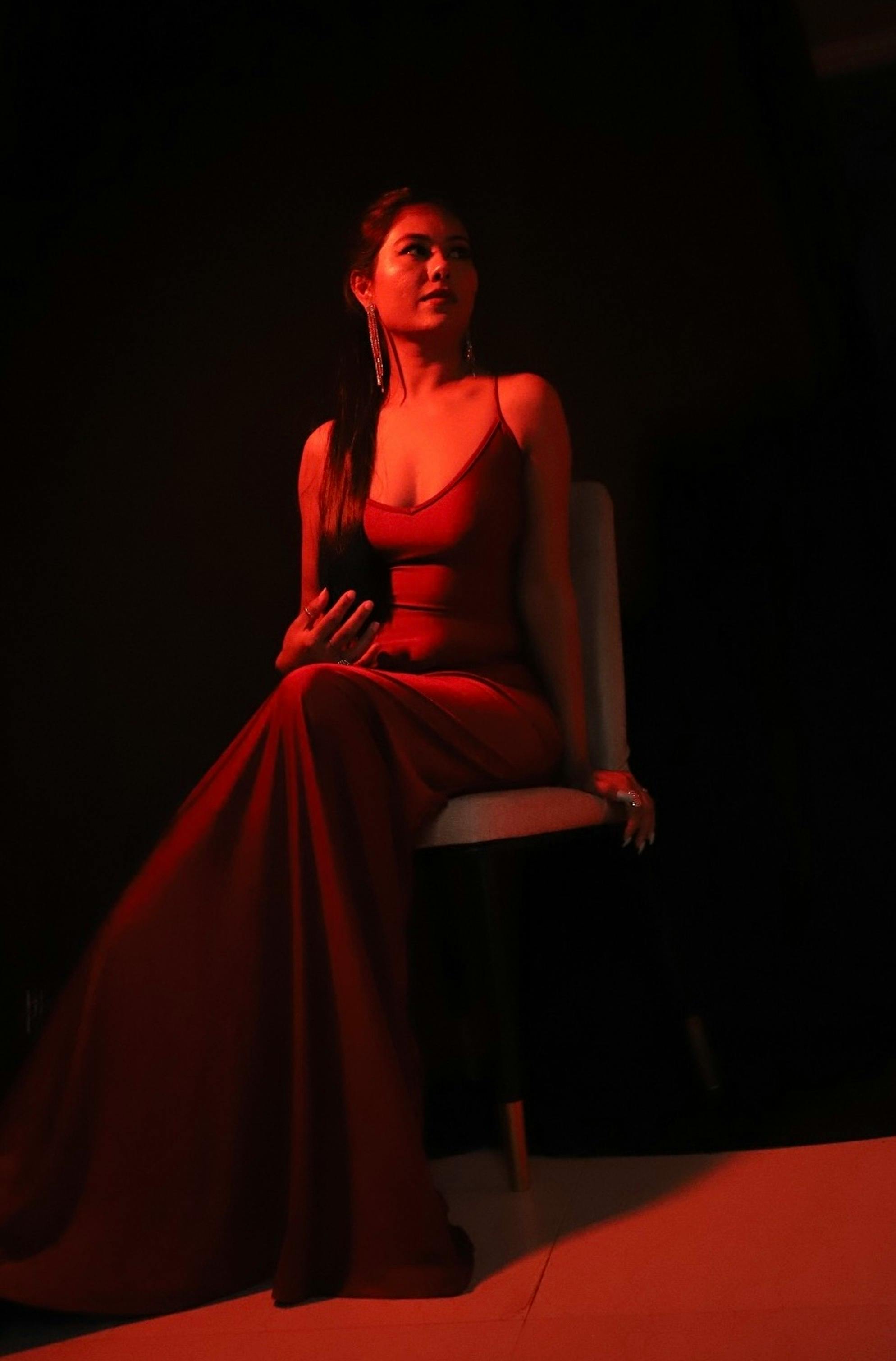 a woman in a red dress sitting on a chair