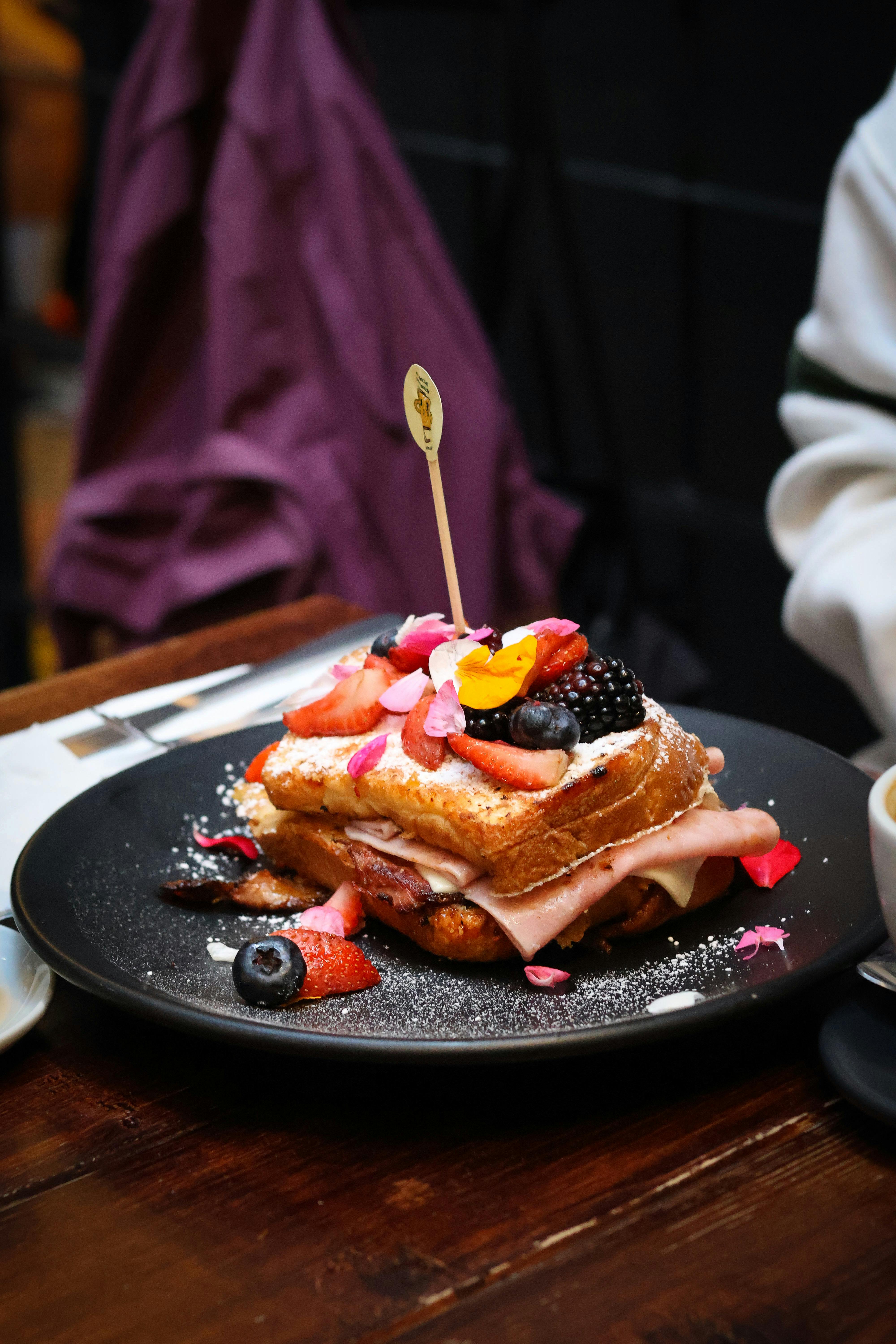 Indulgent French toast topped with mixed berries and edible flowers, perfect for a gourmet breakfast.