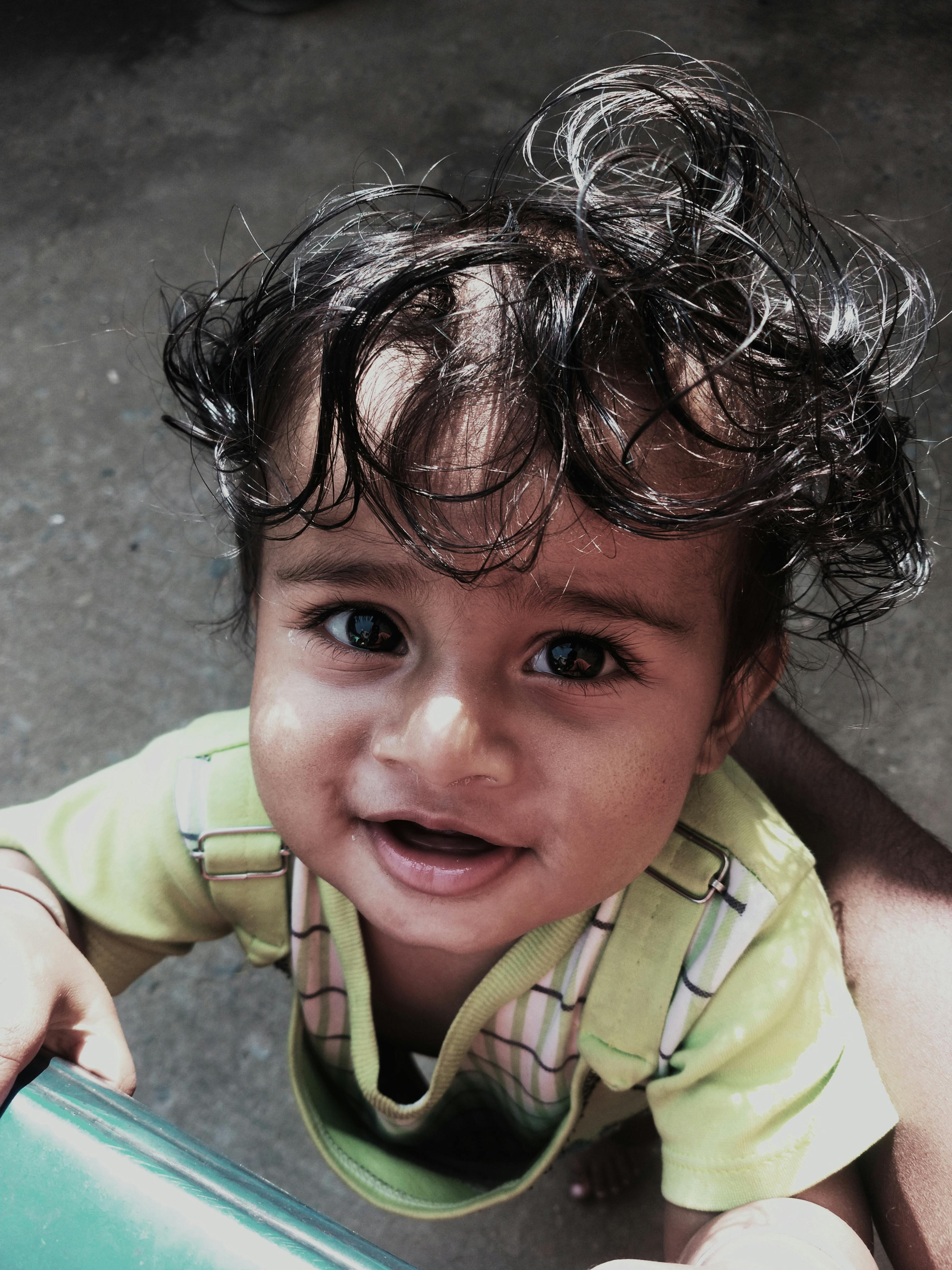 a baby with curly hair sitting on a chair