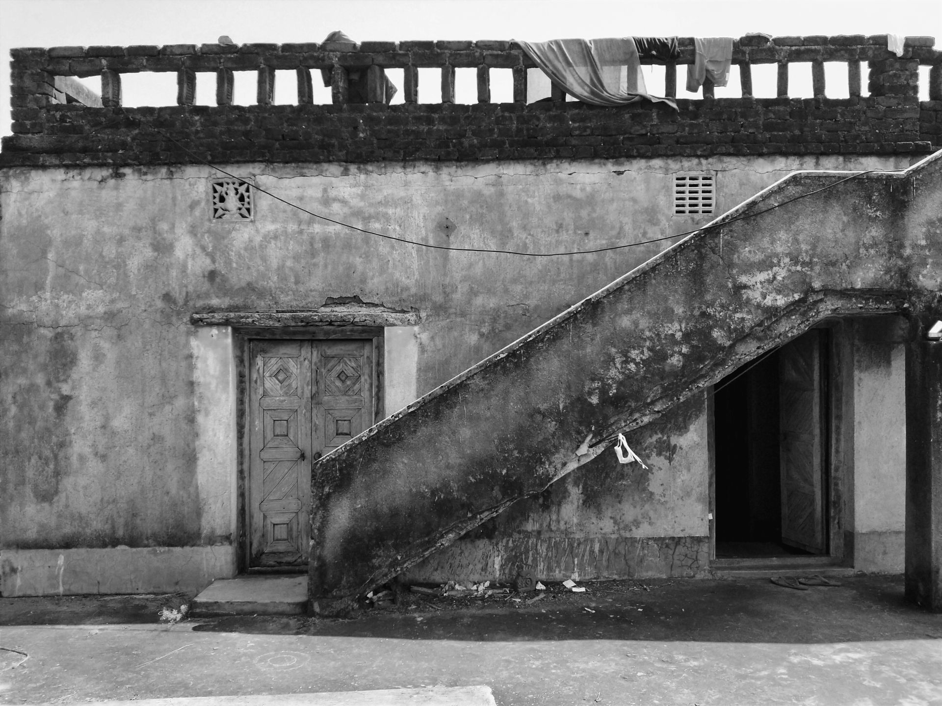 Black and white photo of an old urban building facade with stairs and laundry.
