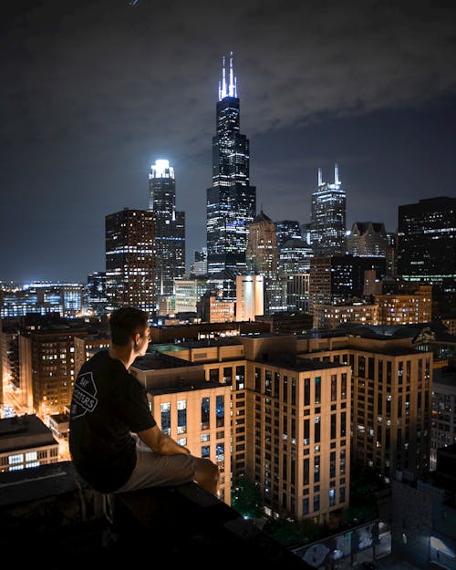 Free Man Sitting On Rooftop At Night Stock Photo