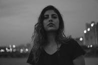 一位年轻女子晚上站在户外，肖像以醒目的黑白呈现