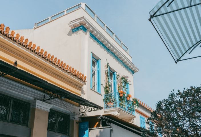 Explore a charming traditional building in Athens with vibrant blue shutters and balcony.