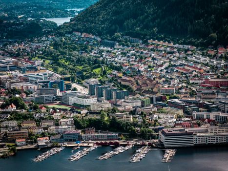 Panoramic view of Bergen, Norway's colorful buildings and marina against lush green hills.