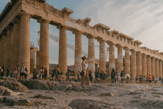 Tourists visiting the ancient Parthenon temple in Athens during a warm summer day.