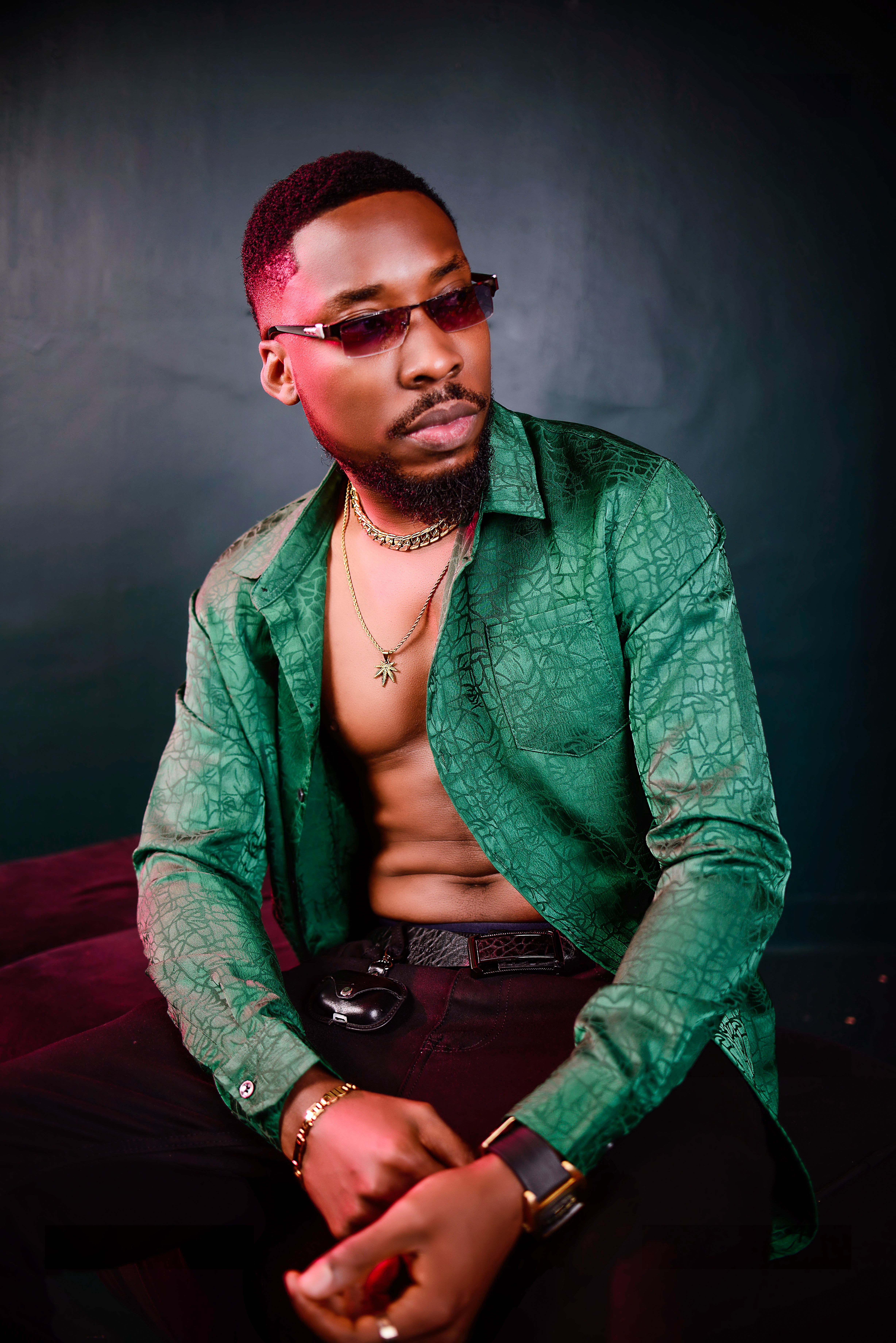 Portrait of a stylish African man wearing a green shirt and sunglasses, exuding cool confidence.