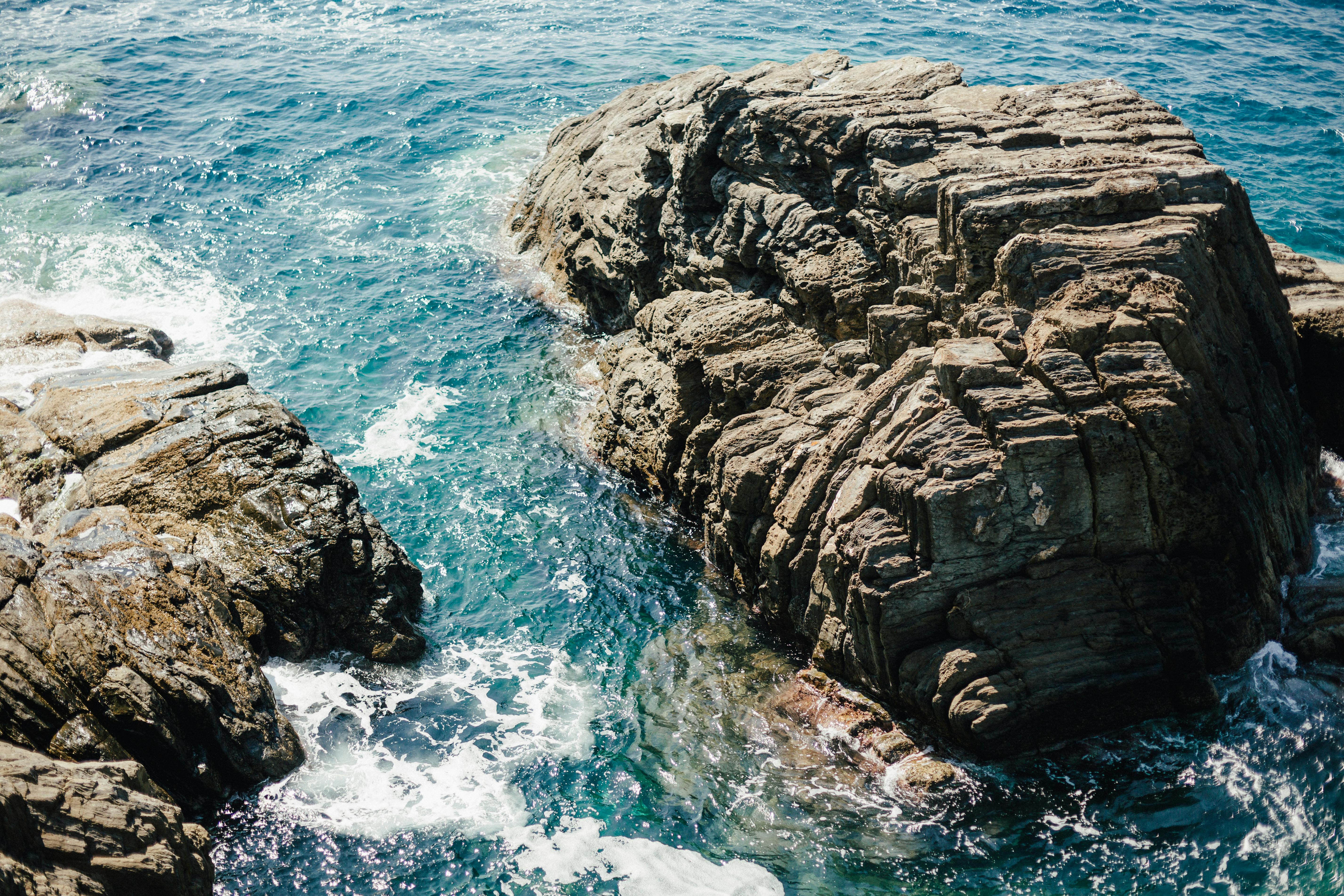 Scenic view of rugged rocks by clear turquoise sea in Cinque Terre, Italy.