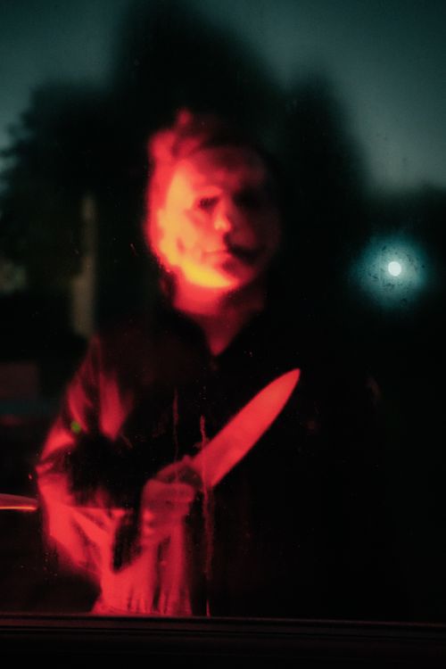 Free Creepy silhouette holding a knife, lit in blood-red light, perfect for Halloween themes. Stock Photo