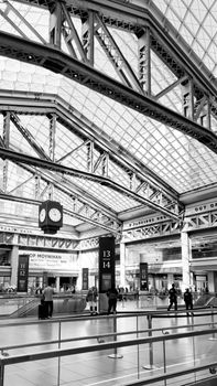 Black and white view of Moynihan Train Hall, showcasing modern architecture and travelers in NYC.