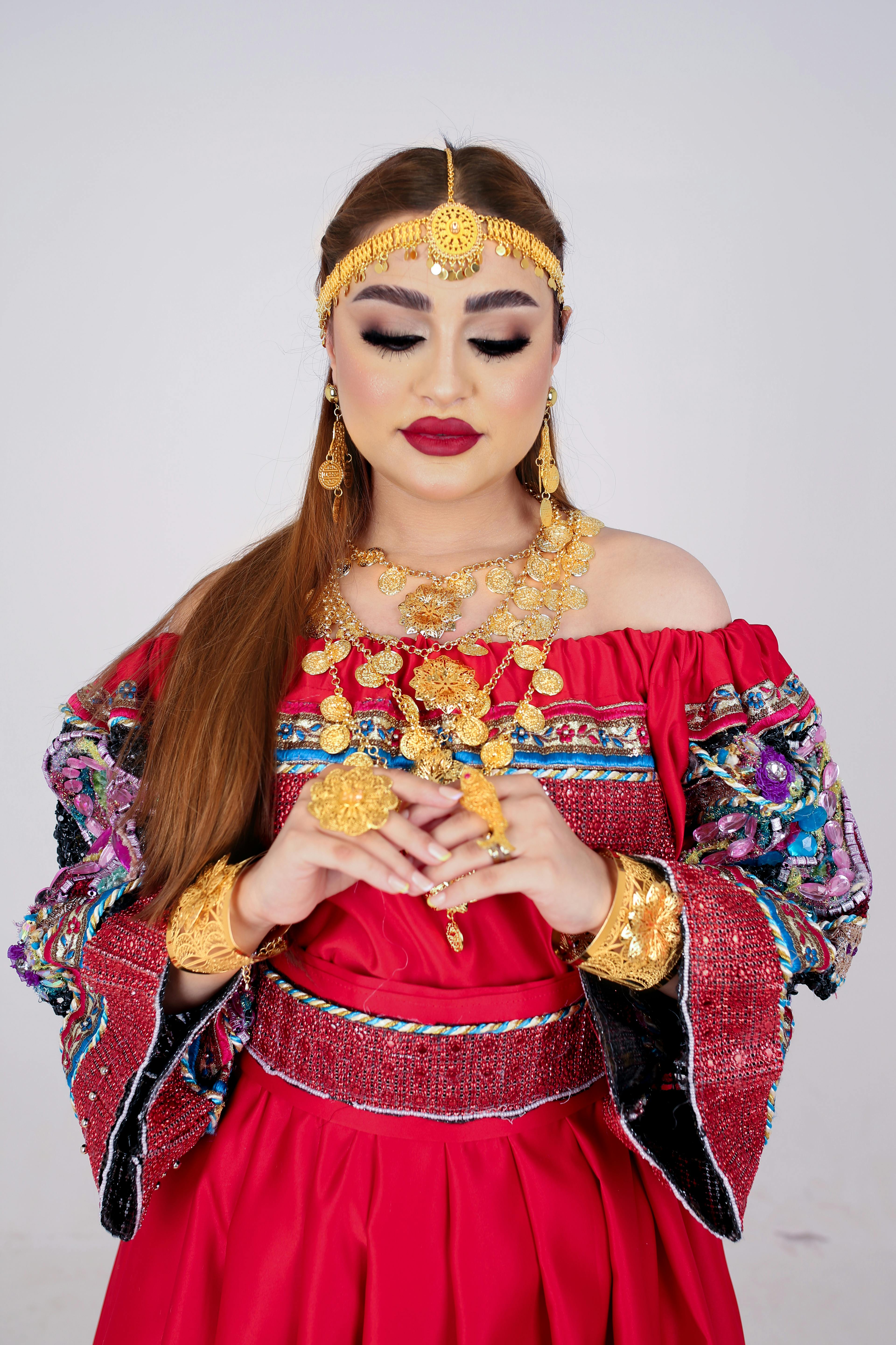 A woman in a colorful traditional Libyan dress, adorned with gold jewelry, embodying cultural elegance.