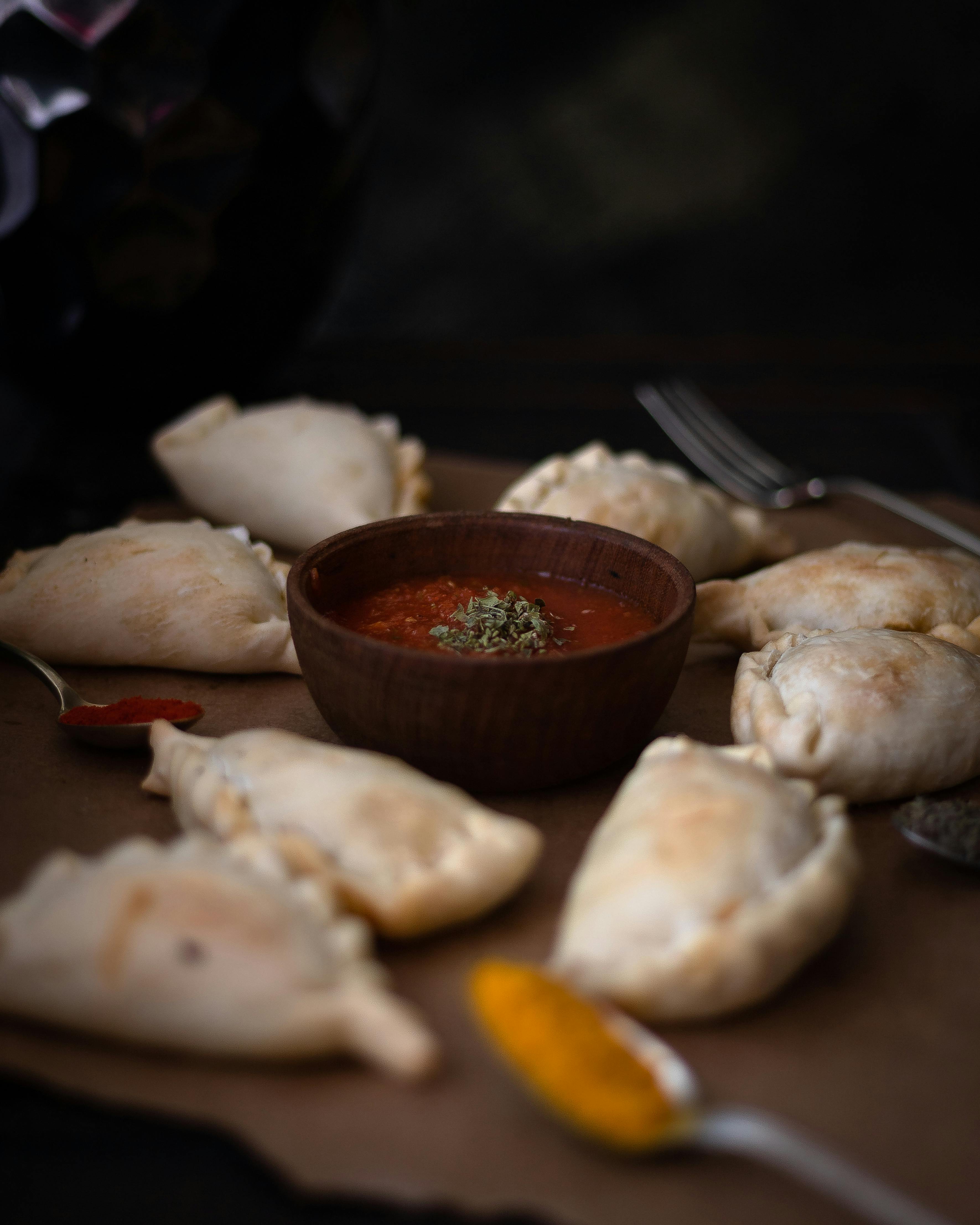 a plate of empanadas with sauce and a spoon