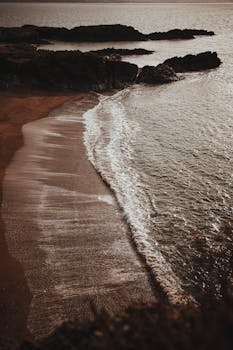 Captivating view of a tranquil beach cove during golden hour with waves gently washing the shore.