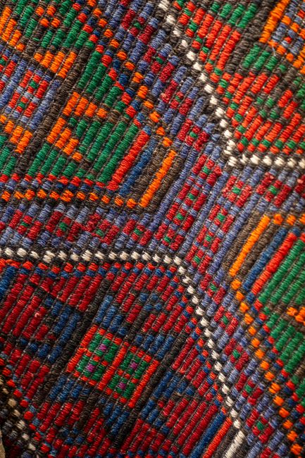 Close-up view of a colorful handmade geometric pattern woven textile, showcasing vibrant threads.