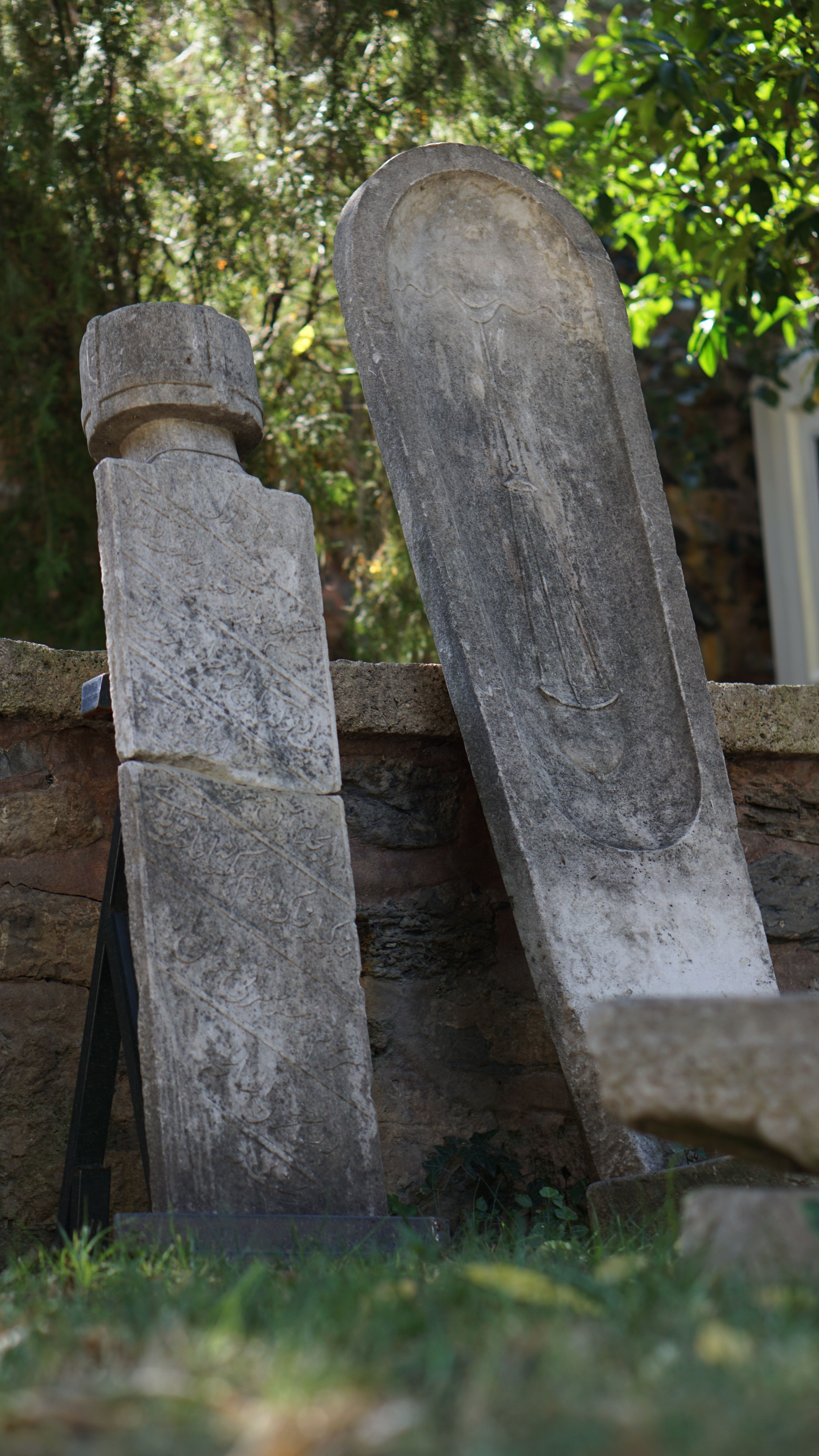 Fotomural Antiguas lápidas de piedra en un cementerio sereno de Estambul, rodeadas de vegetación.