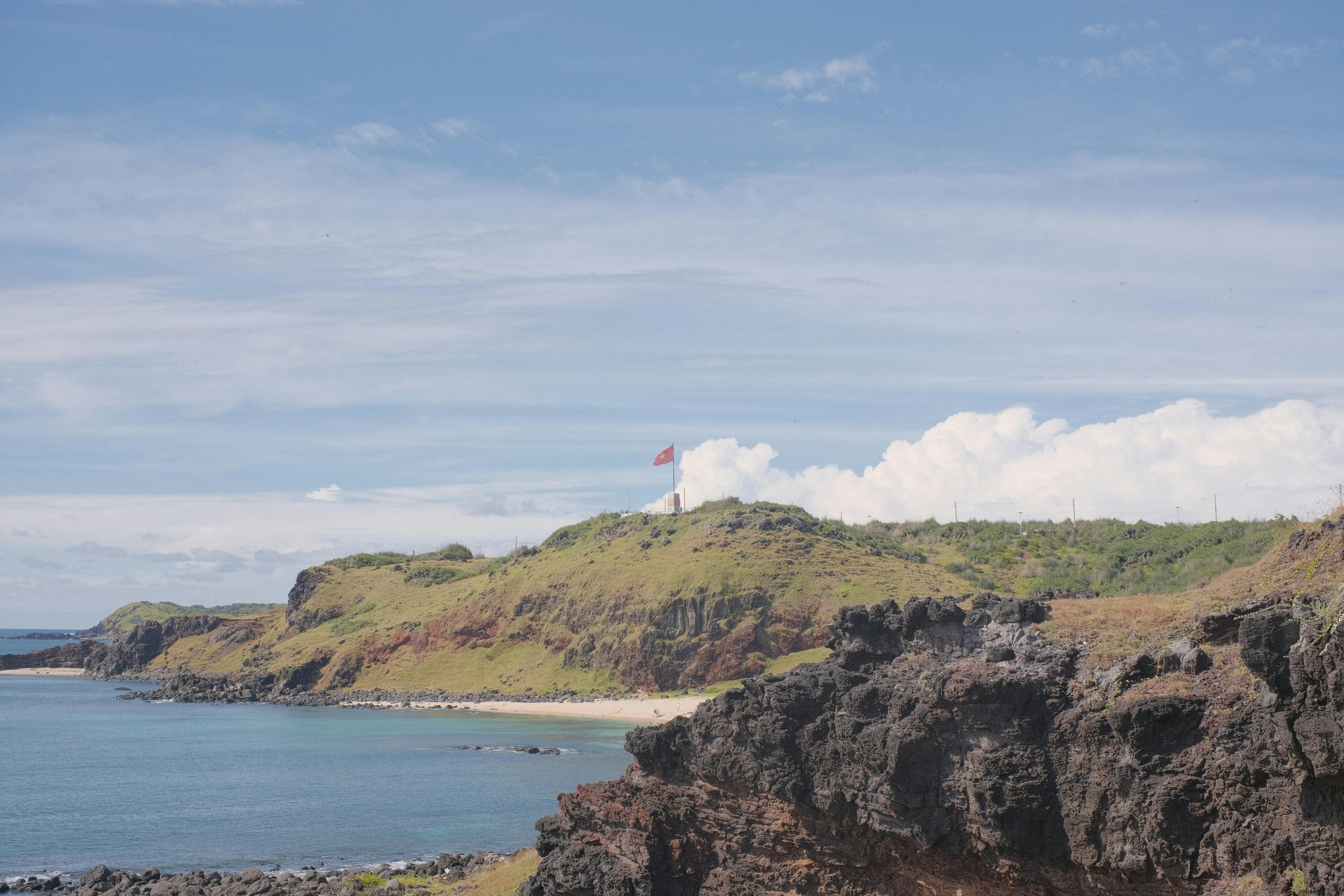 Lighthouse on the rocky coastline of Phú Quý Island, Vietnam, overlooking the ocean.