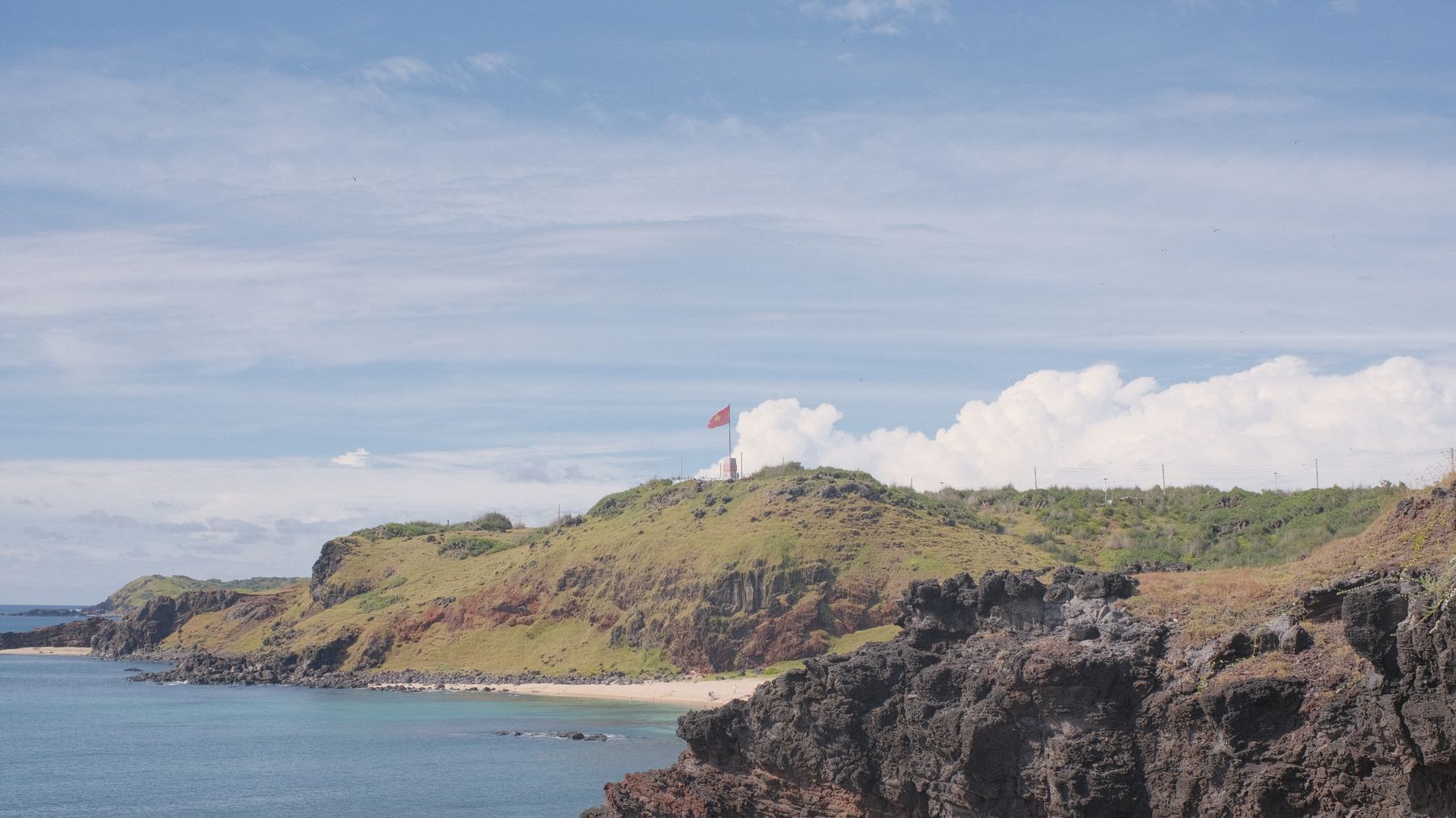 Lighthouse on the rocky coastline of PhΓΊ QuΓ½ Island, Vietnam, overlooking the ocean.